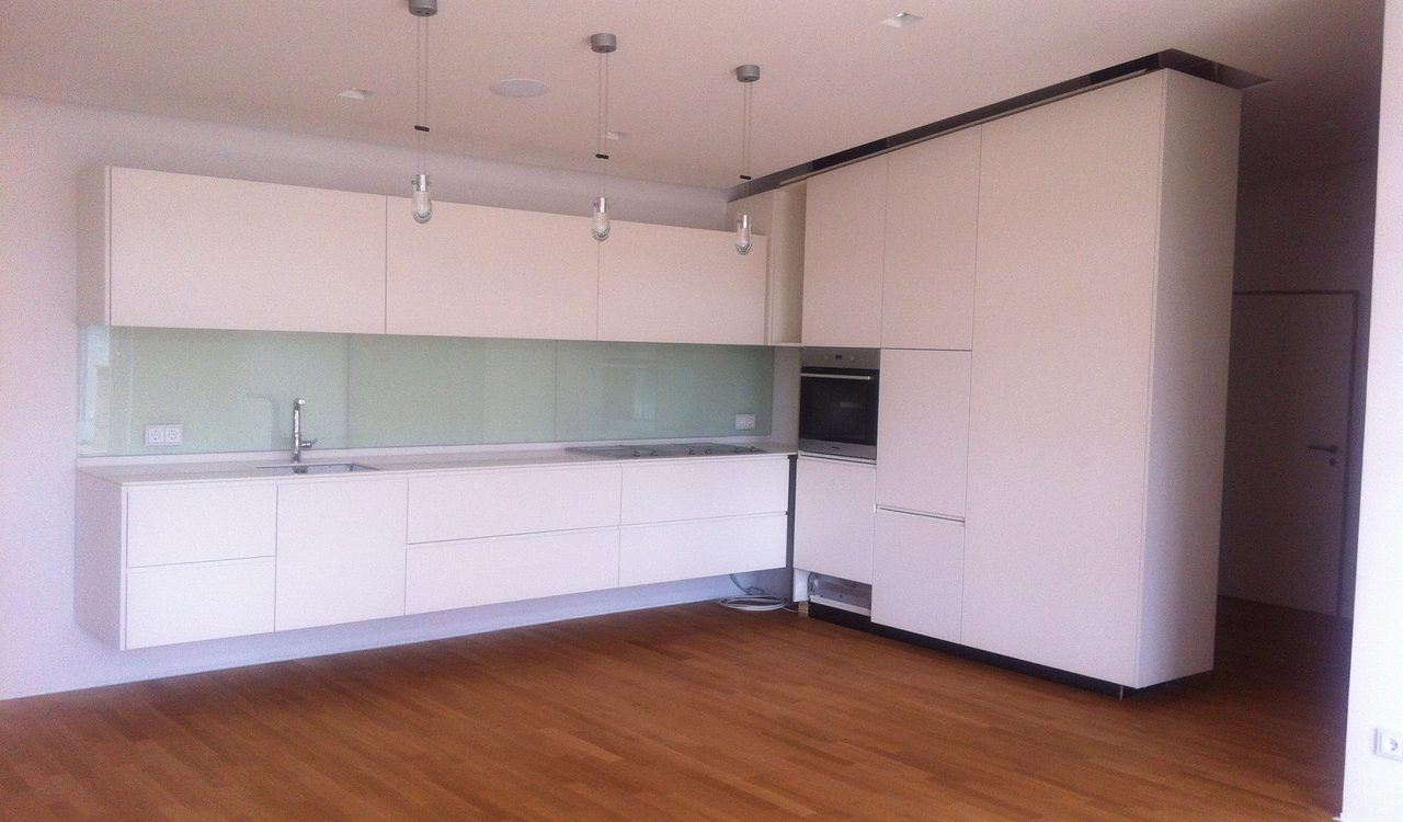 Weiße Küchenzeile mit Holzboden in einer leeren Wohnung