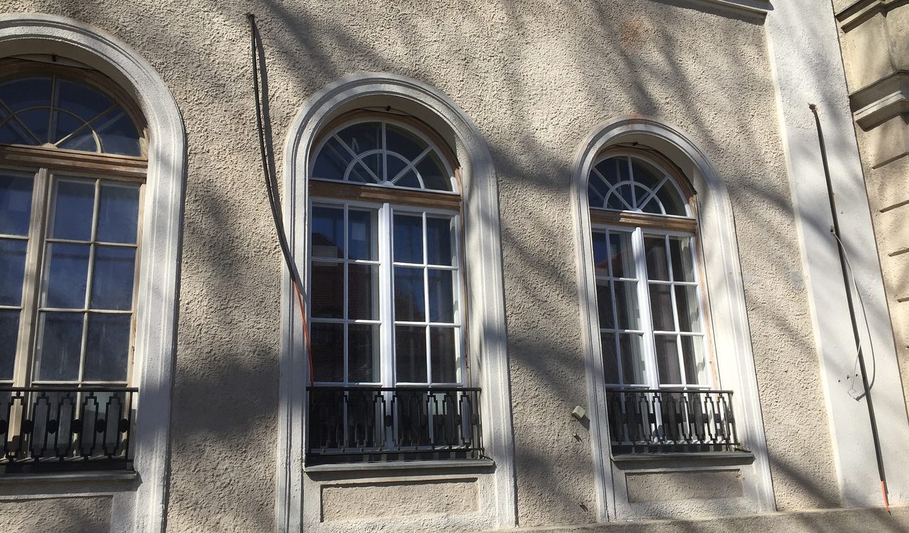 Detail einer Altbaufassade mit hohen Rundbogenfenstern und Ziergesims