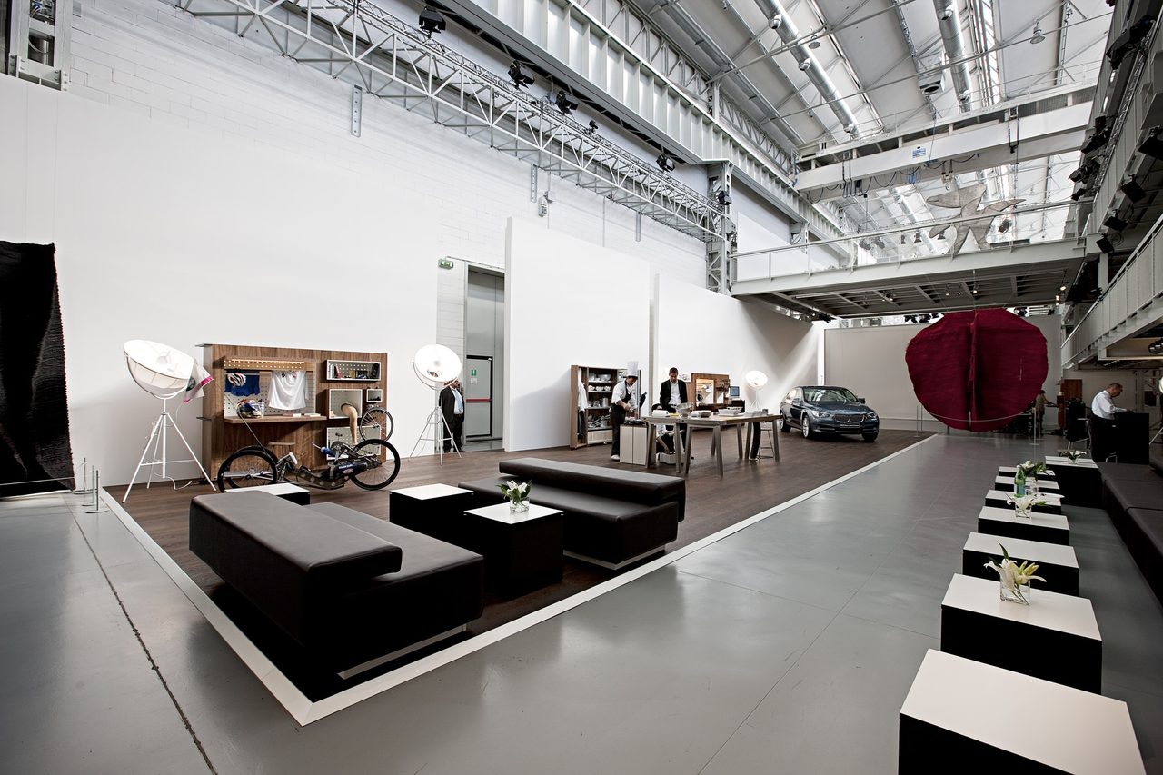 Ausstellungsfläche mit dunklen Sitzlandschaften und Themeninseln in einer Halle
