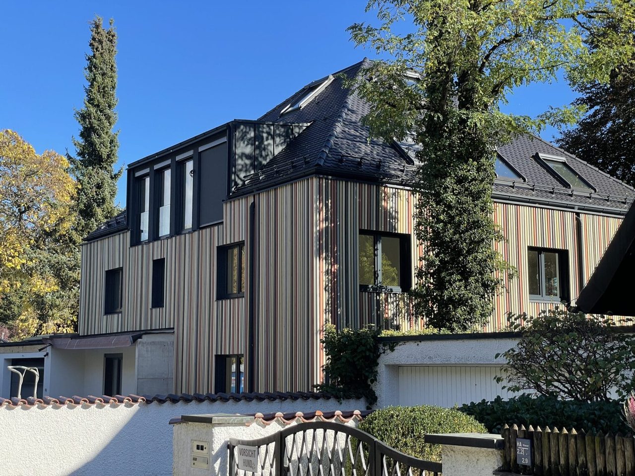 Aufgestocktes Wohnhaus mit vertikal gegliederter Holzfassade und Dachterrasse