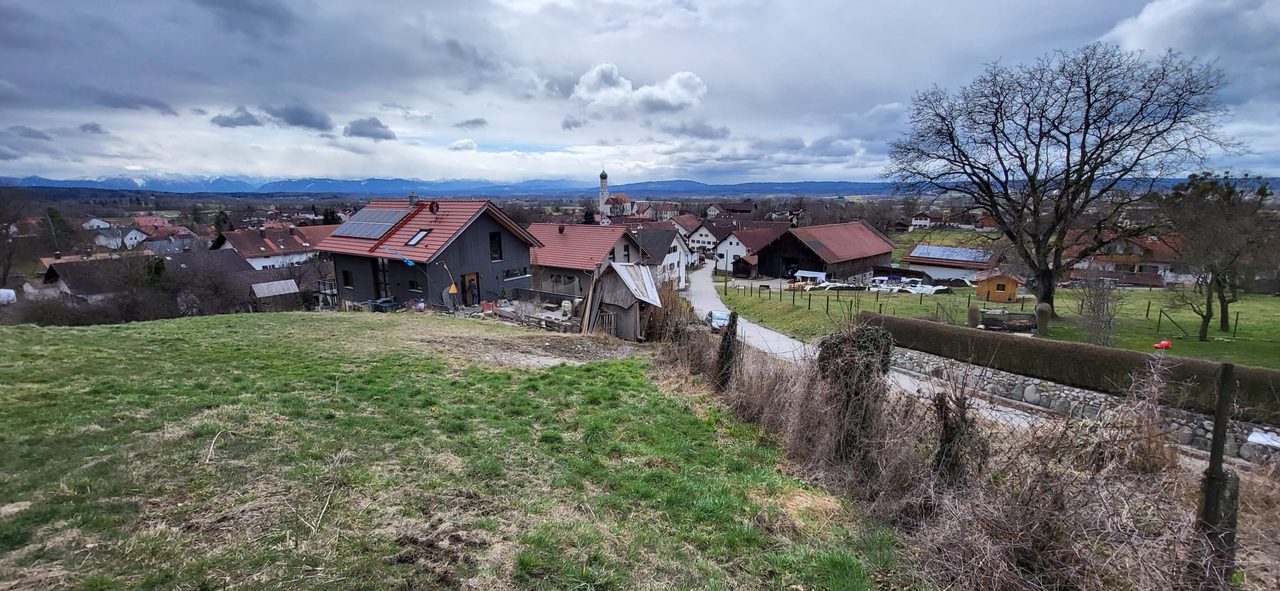 Unbebautes Grundstück am Ortsrand mit Blick über das Dorf ins Voralpenland